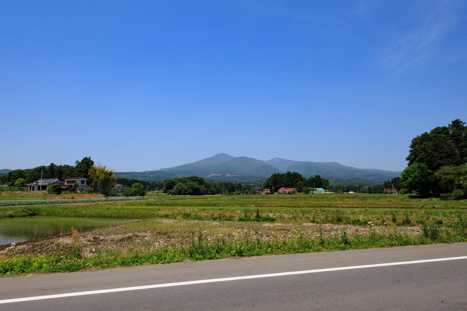 安達太良山を背景に、春の新緑が映える福島県の田んぼ風景