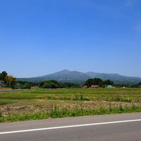 安達太良山の新緑を背景に、春の田んぼから望む遠景の写真