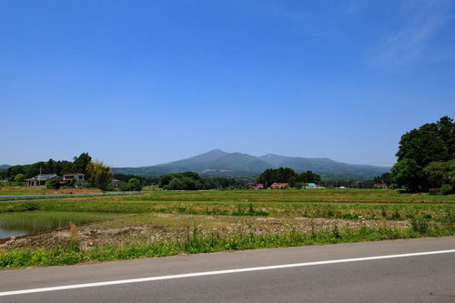 安達太良山の新緑を背景に、春の田んぼから望む遠景