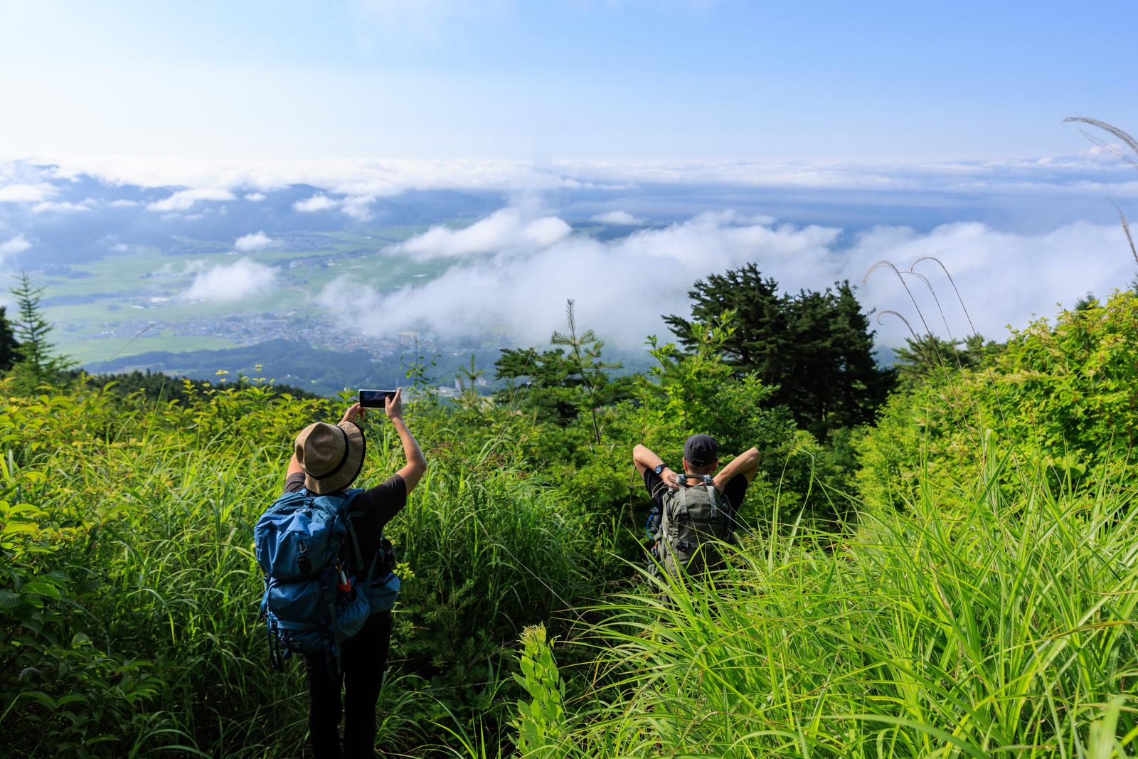 磐梯山の山頂から雲海と遠景を眺める2人の登山者