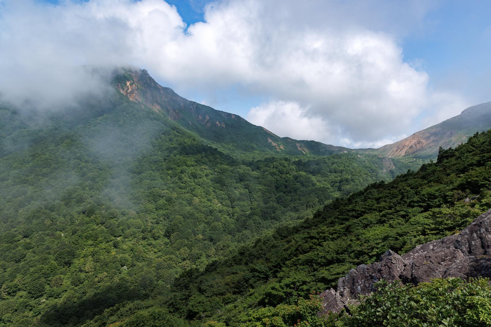 雲に包まれた磐梯山の稜線と樹林に覆われた山肌