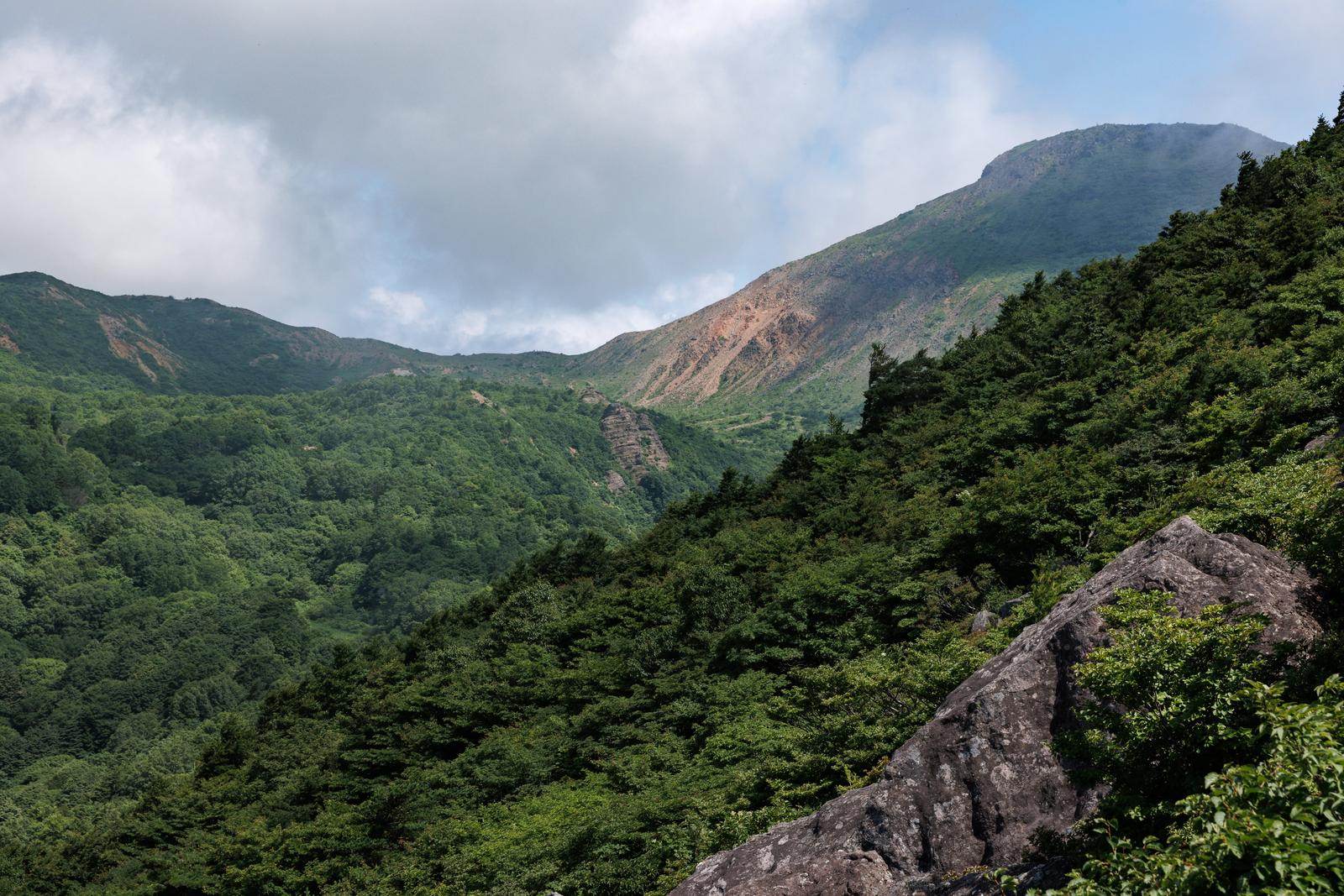 磐梯山の稜線に落ちる雲の影と樹林帯の山岳風景