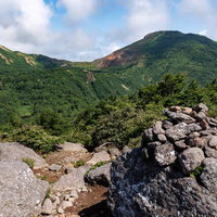 赤埴山山頂のケルンと磐梯山の山々を望む登山風景の写真