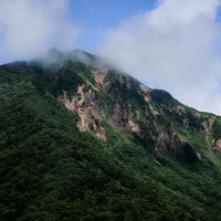 緑に覆われた山肌と山頂の雲がかかる福島県の磐梯山の写真