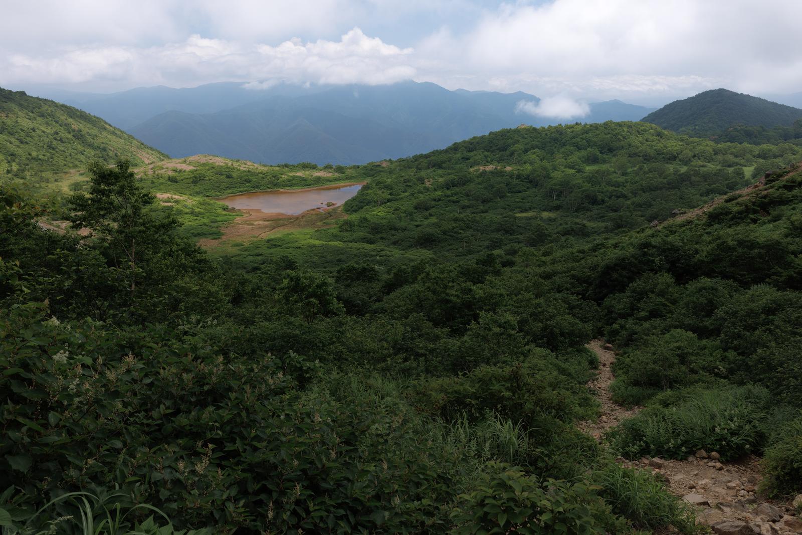 磐梯山の登山口近くの山道から見える沼と遠く連なる山並み