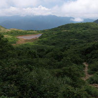 磐梯山の麓、猪苗代町の登山口から見える沼と緑の山並みの写真