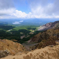 猪苗代町の磐梯山登山口から眺める崖と遠景の山々の写真
