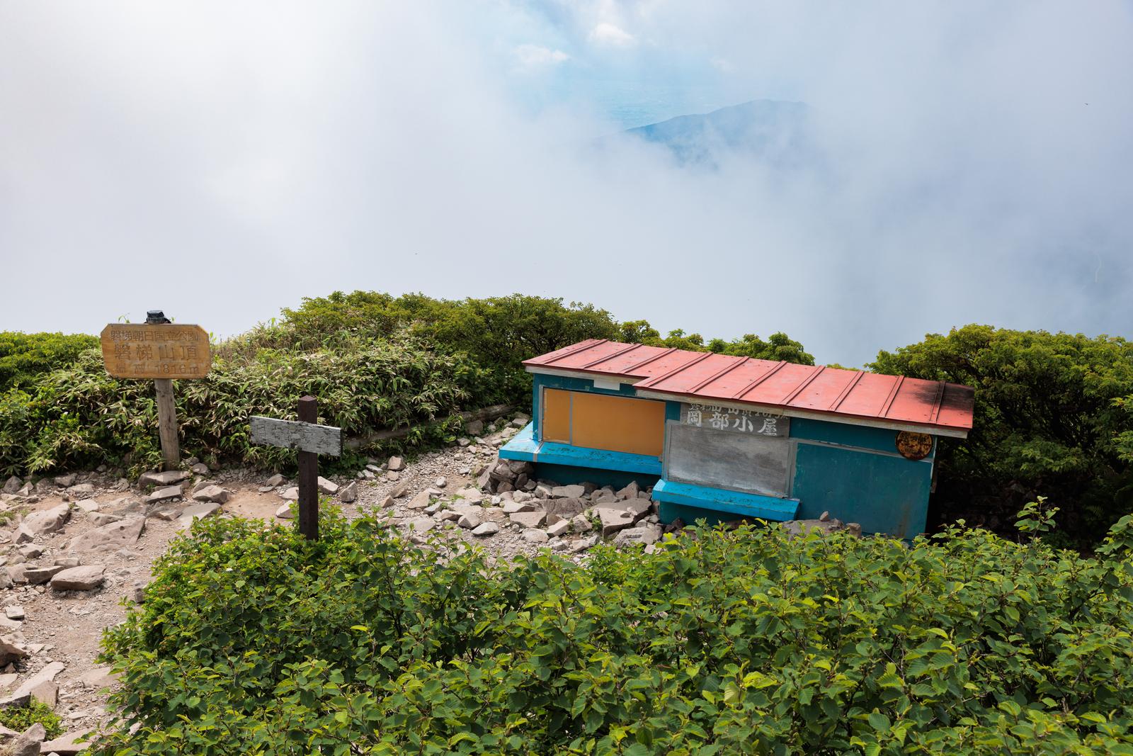 猪苗代町の登山道にある赤い屋根の岡部小屋。磐梯山頂付近に位置し、周囲は樹林と岩に囲まれている。