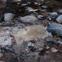 磐梯山の湿地帯に広がる泥地と転がる岩、登山道の地形の写真