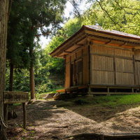 杉の大木に囲まれた平田村の山鶏滝不動尊のお堂の写真