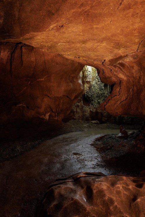 あぶくま洞の薄明りの通路と赤褐色の岩肌、鍾乳石の形成物
