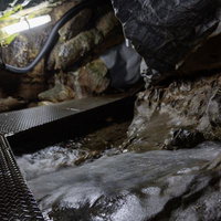 懐中電灯の光が照らす入水鍾乳洞の濡れた通路の写真