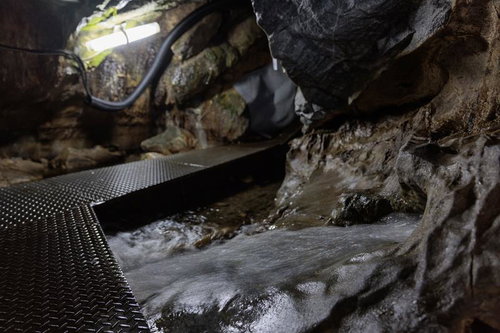 懐中電灯の光が照らす入水鍾乳洞の濡れた通路