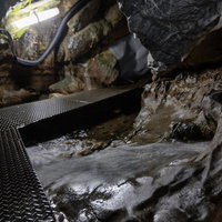 天井が低い入水鍾乳洞の洞内通路を歩く懐中電灯探検の写真