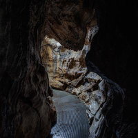 入水鍾乳洞の奥へ続く濡れた通路と石灰岩層の写真