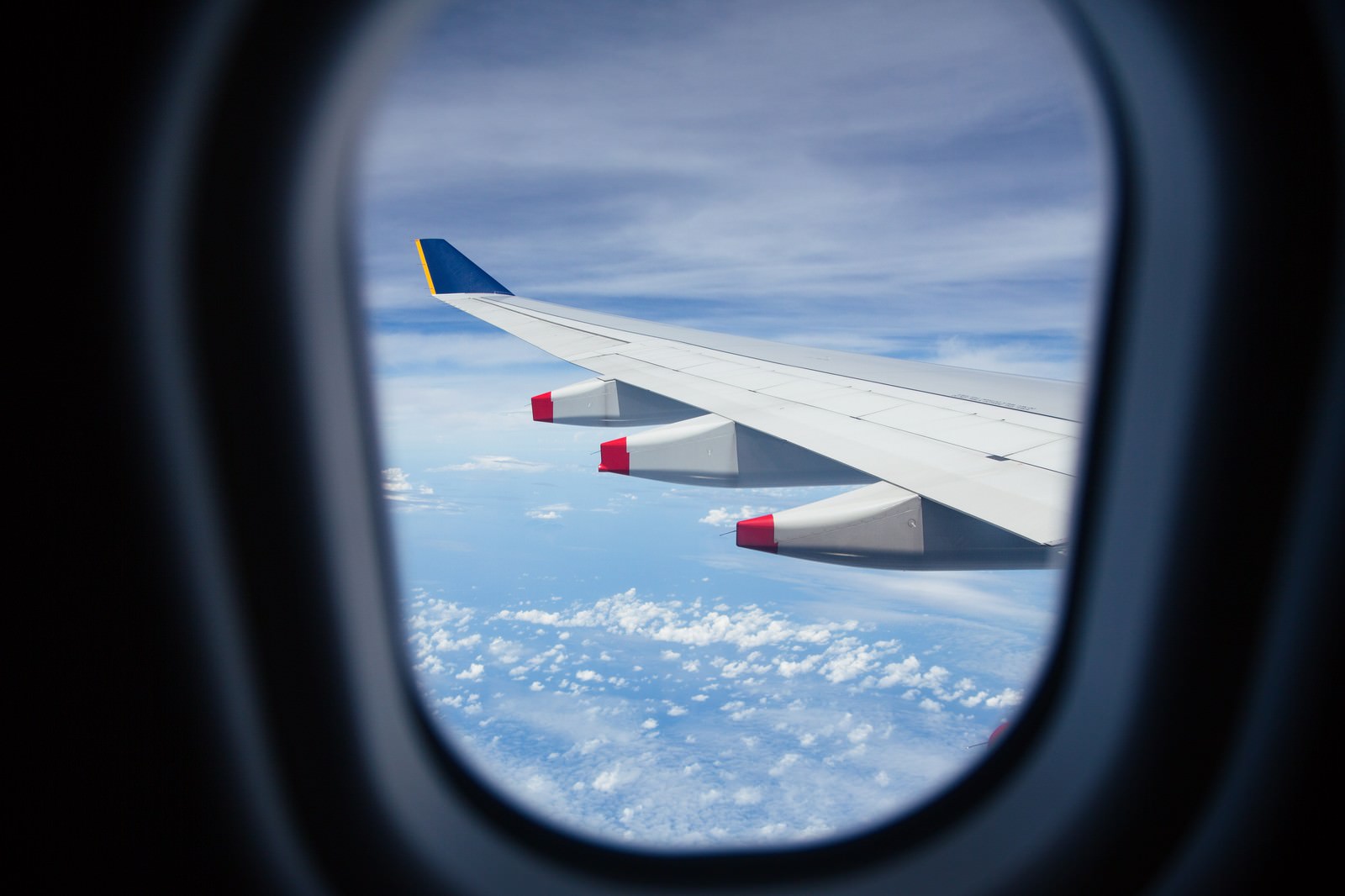 旅客機の窓から見える翼と一面の雲