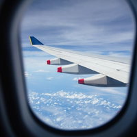 旅客機の窓から見える翼と雲海、上空からの飛行風景の写真