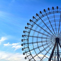 雲が浮かぶ青空を背景にした大きな観覧車の写真