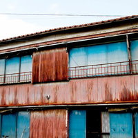 トタンの壁が朽ちて錆びた古いアパートの外観の写真