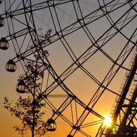 オレンジの空を背景にシルエットになった夕焼けの観覧車の写真