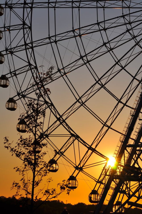 オレンジの空を背景にシルエットになった夕焼けの観覧車