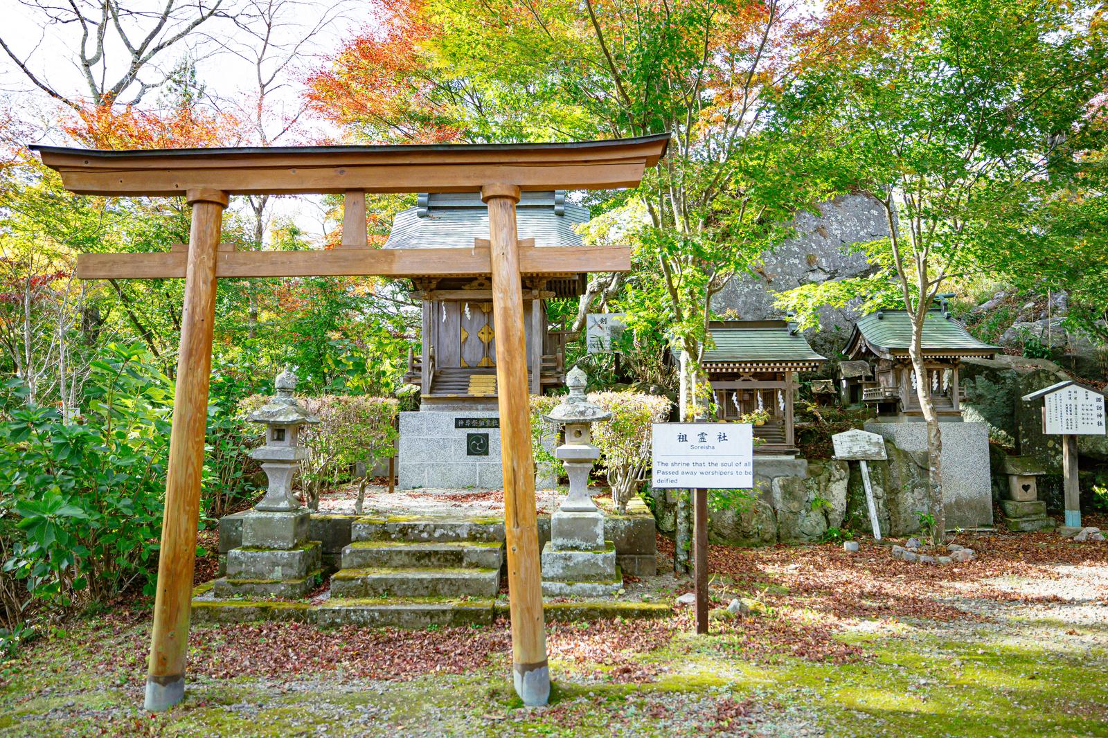 Large wooden torii gate and shrine buildings surrounded by autumn foliage at Isitsuchinokiya Shrine