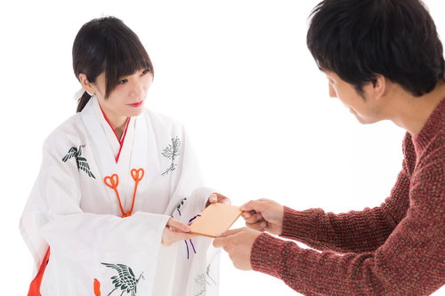 絵馬を参拝者に手渡す巫女