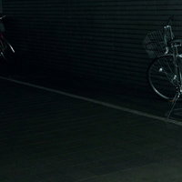 暗い駐輪場に並ぶハンドルとサドルの自転車の写真