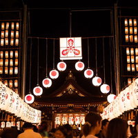 提灯が並ぶ夜の神社と参拝者の写真