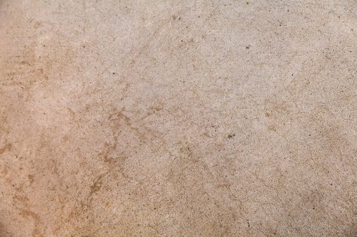 細かい粒と黒い点が散らばるベージュから茶色の日本家屋の石壁テクスチャー