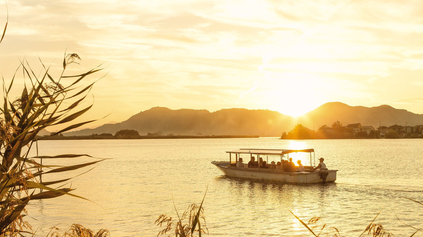 夕焼けの湖上で観光客を乗せて航行する船