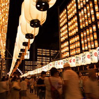 万灯祭の提灯壁と行き交う人々の写真