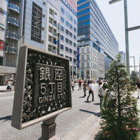 銀座5丁目と書かれた案内板、行き交う人混みの写真