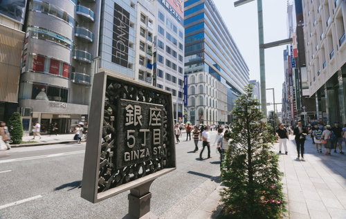 銀座5丁目と書かれた案内板、行き交う人混み