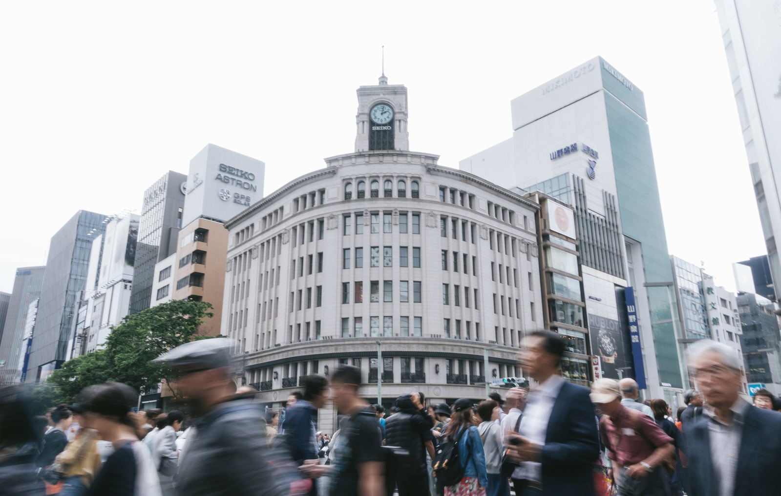 銀座4丁目交差点で和光の時計台を背景に行き交う大勢の人々