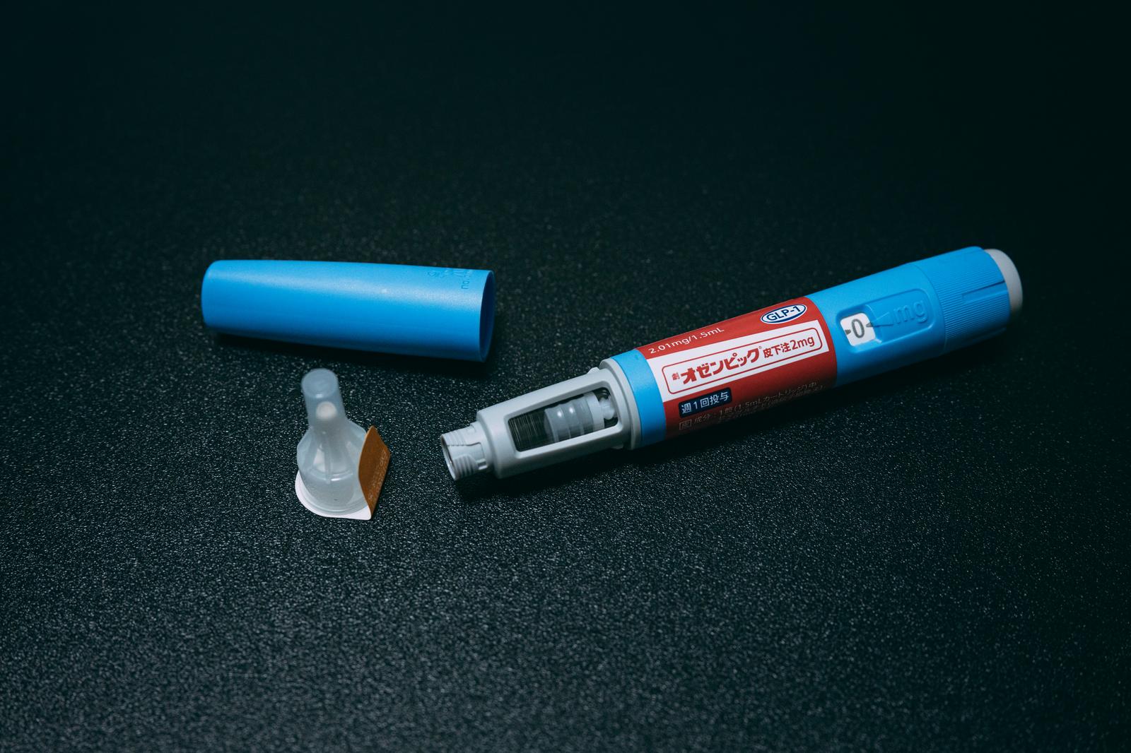 青と赤のGLP-1受容体作動薬の自動注射ペン、キャップ、注入針