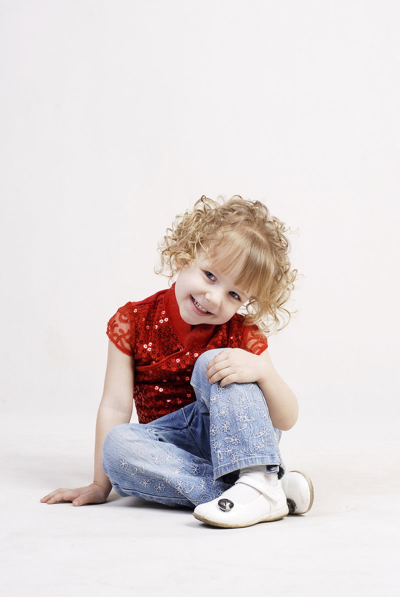 床に座る金髪くるくる髪の幼い女の子［モデル：モデルファクトリー］