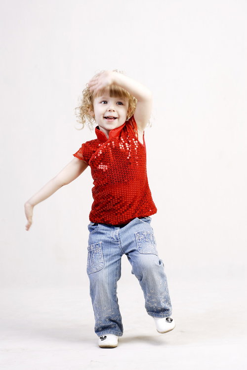 赤いシャツを着て手を振る金髪の女の子の笑顔