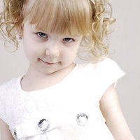 白いお洋服を着たブロンドヘアの子供の笑顔の写真