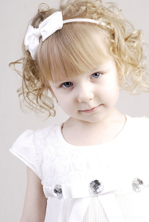 パーティ用におめかしした、ブロンドヘアのカール髪の幼い女の子