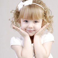 白いドレスを着て可愛さアピールをする笑顔のブロンドヘアの女の子の写真