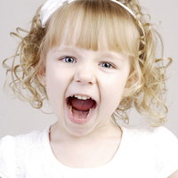 叫び声をあげ叫ぶブロンドヘアの女の子の驚きの表情の写真