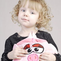 おどけた表情でぶたのバッグを持つ幼い女の子の写真