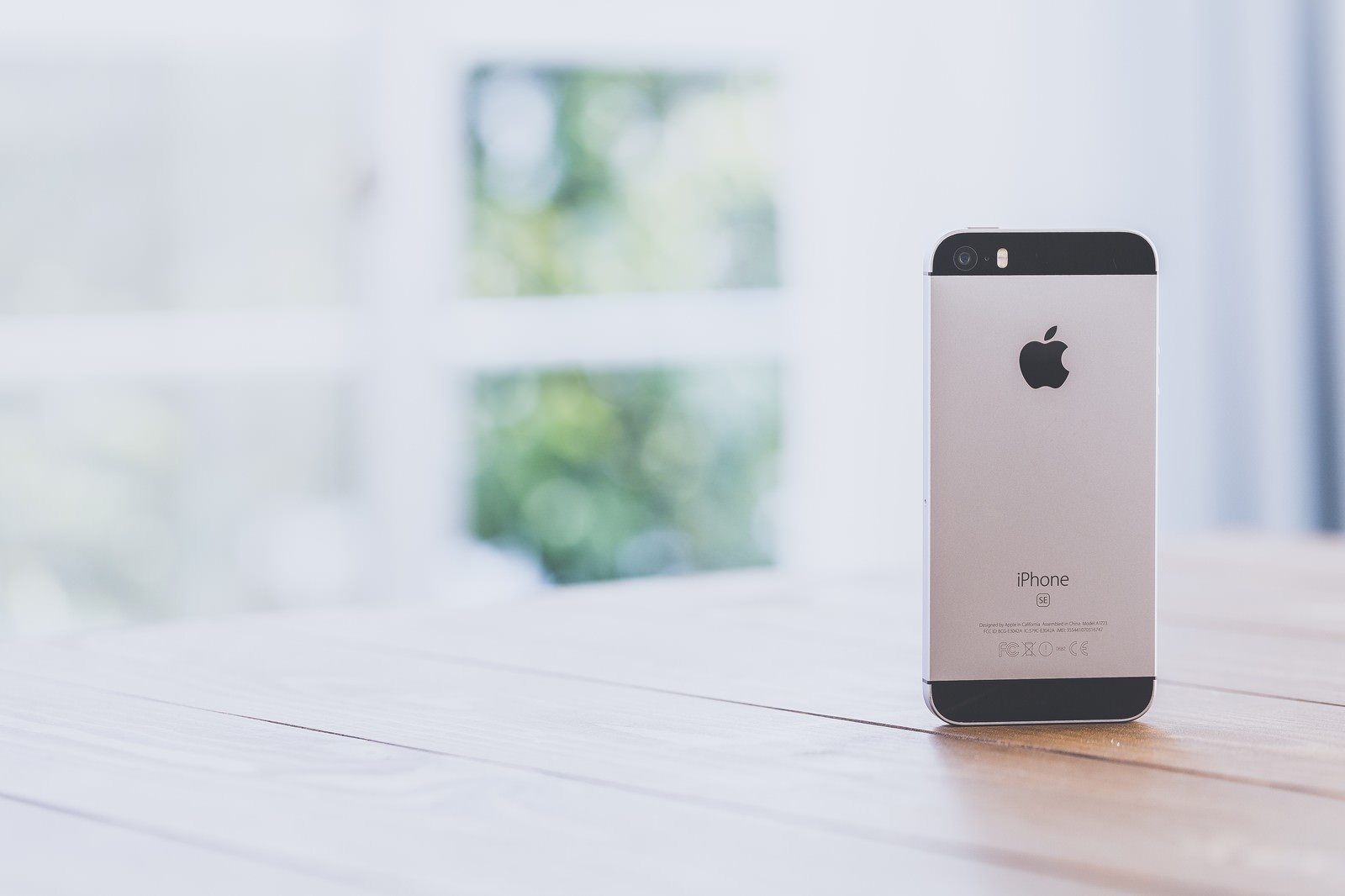 木製テーブルの上に縦置きされたiPhoneの背面