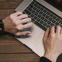 スマートウォッチで時間を気にするライターのMacBook作業の写真