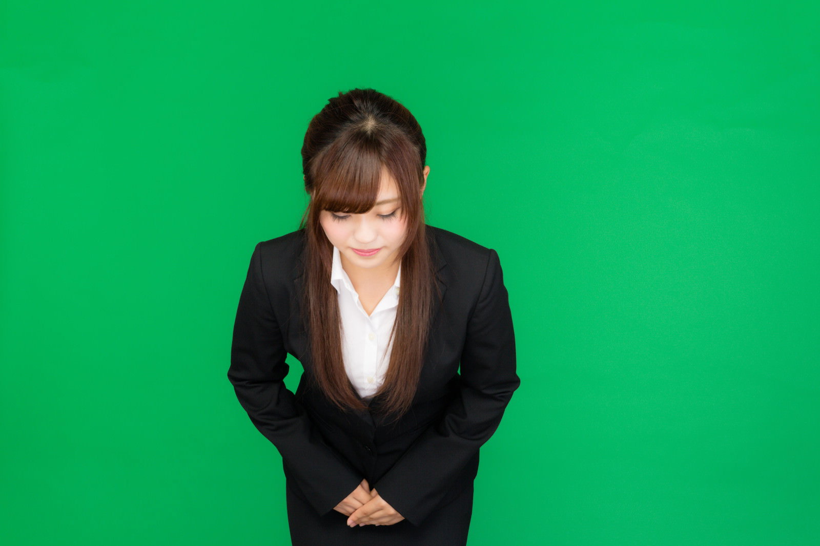 黒いスーツでお辞儀をする女性（グリーンバック）［モデル：河村友歌］