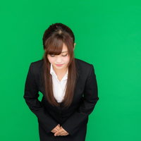 黒いスーツでお辞儀をする女性（グリーンバック）の写真