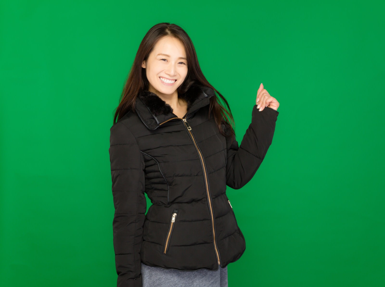 黒いダウンジャケット姿でサムズアップする女性［モデル：土本寛子］