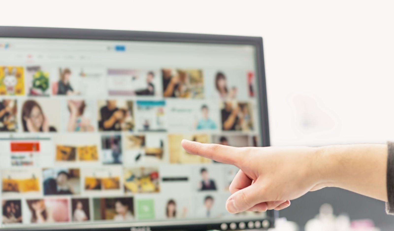 モニター画面の画像一覧に向かって右手の人差し指で指をさす手元のショット