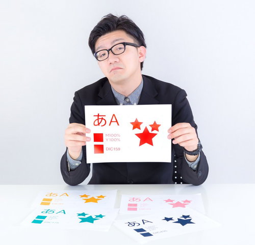 赤い文字の色見本を持つスーツの男性